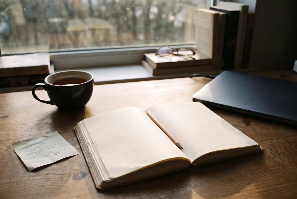 A paper planner open to a blank week on a desk in late-afternoon light, with a pencil and a cup of tea.